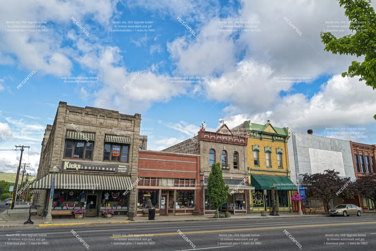 A vibrant downtown streetscape featuring the Kicks sportswear storefront set in beautifully preserved, colorful historic architecture. The facades capture the energy of local boutiques and small businesses lining the street.
